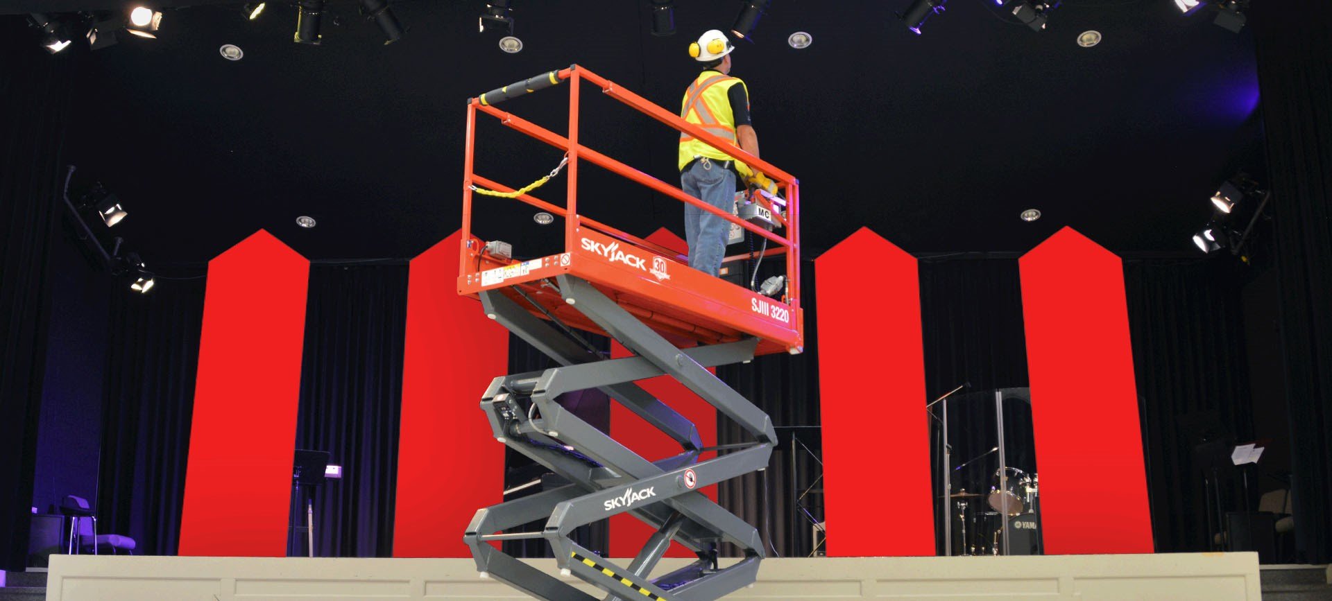 Technicien faisant de la maintenance sur une scène de spectacle depuis un échafaudage hydraulique.