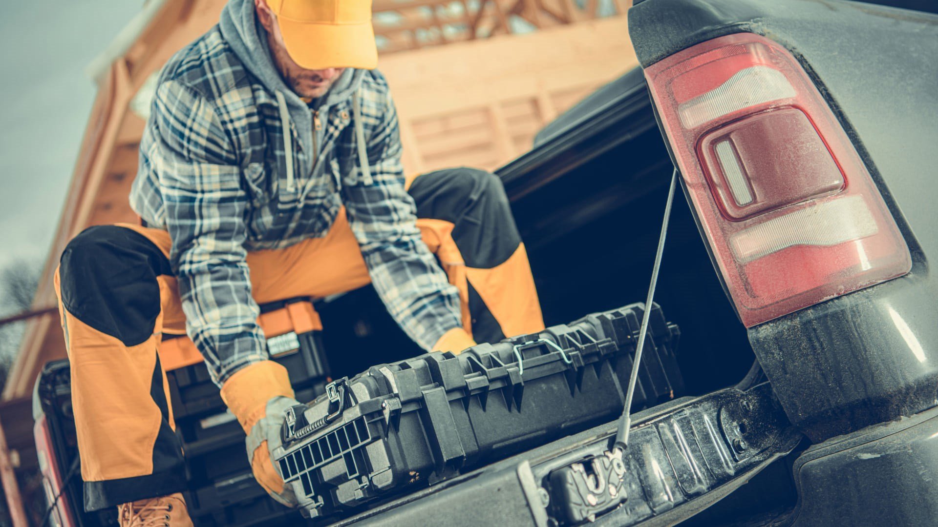 Ouvrier chargeant une caisse à outils dans un camion sur un chantier, illustrant le service de ramassage et de retour flexible offert par Simplex.