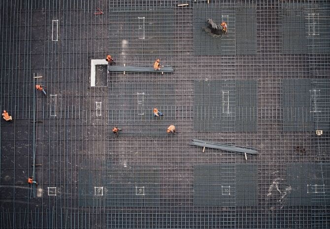 Vue en hauteur d'ouvriers installant des grilles en métal pour les fondations en béton.